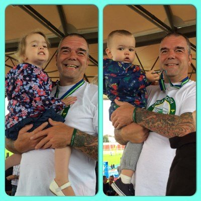Dave Bray holding his kids proudly after running a marathon