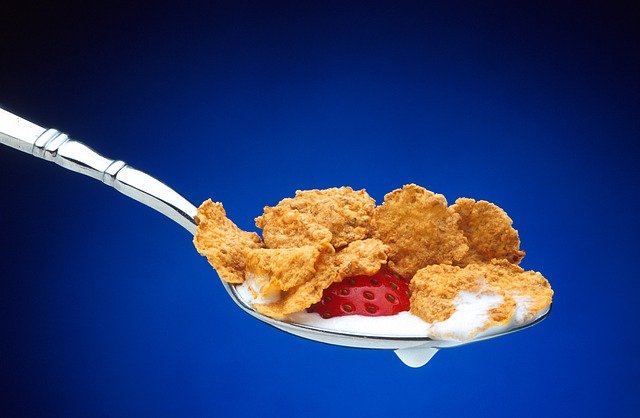 Spoon of cornflakes with milk and strawberry