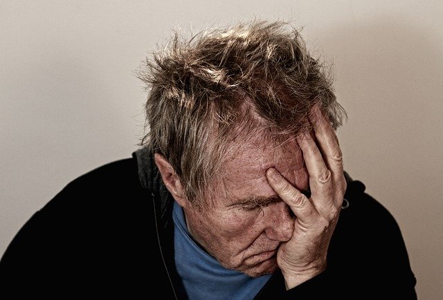 Older man holds his head in his hand