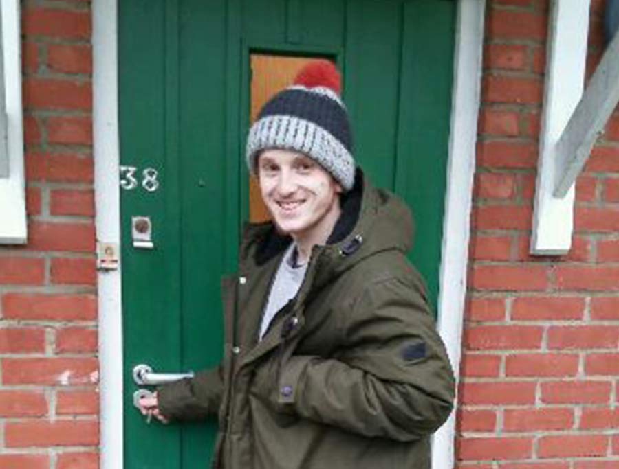 Young man stands outside his new front door
