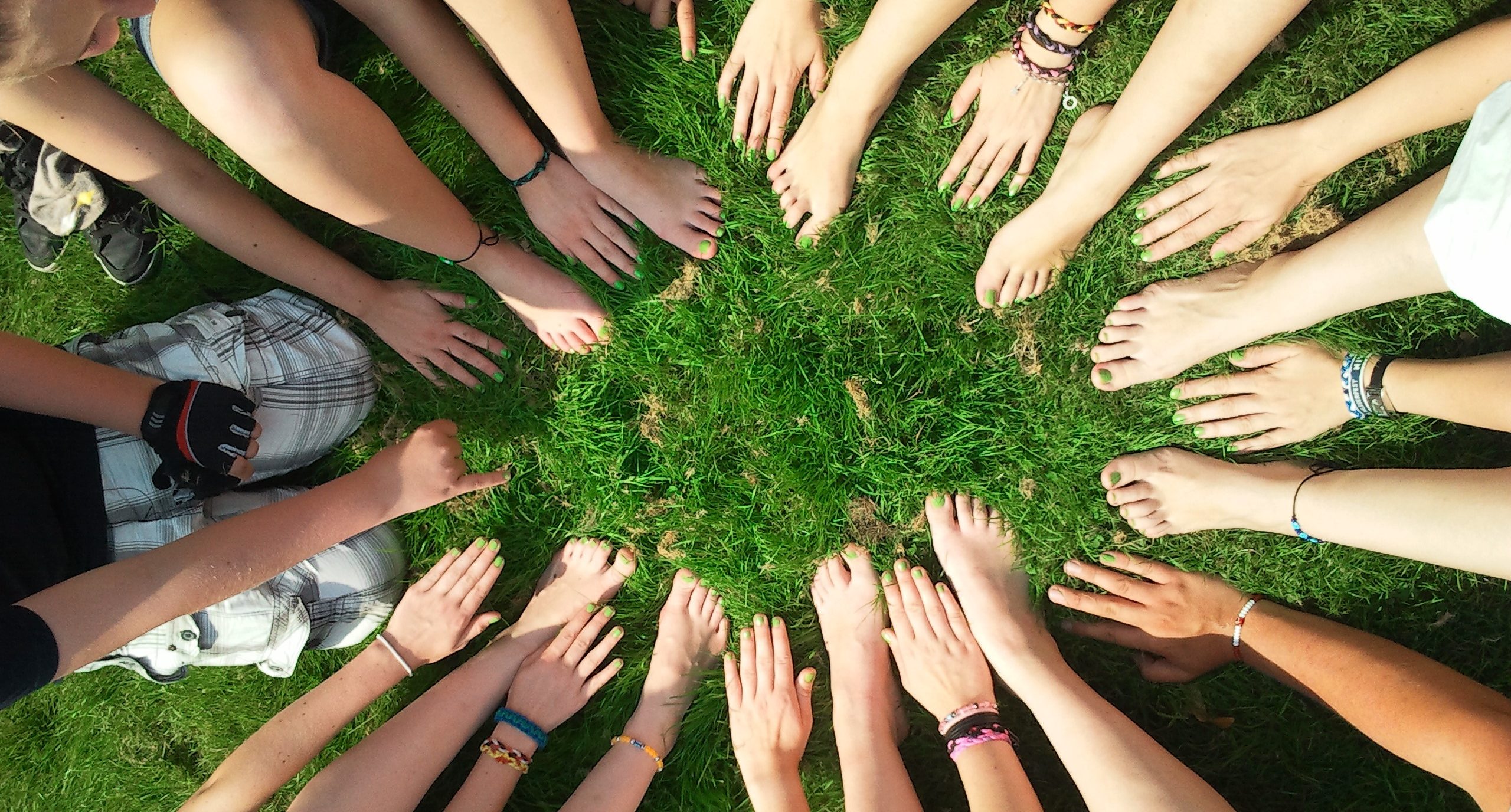 Volunteering Banner - Bare hands and feet form a circle on grass