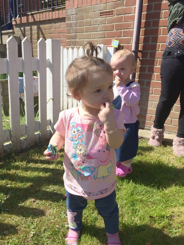Young children enjoy chocolate in the sunshine at an Easter egg hunt