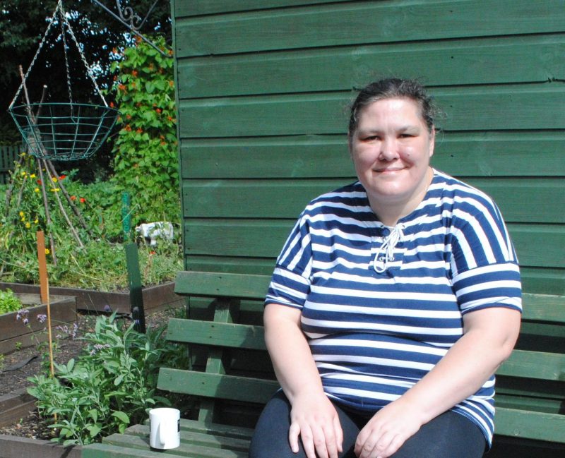Elaine sits on a bench in the hostel garden that gave her her confidence back