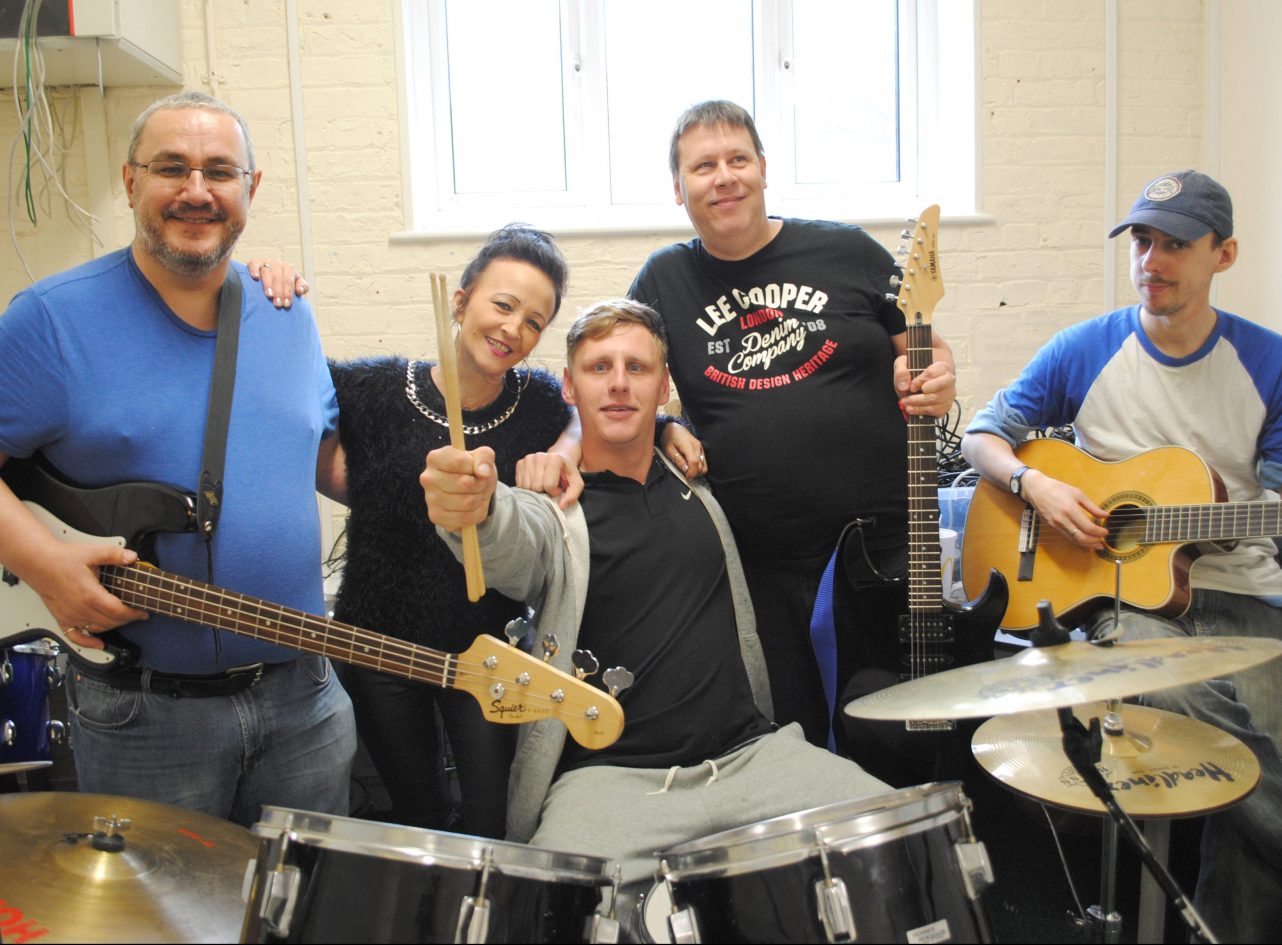 Musicians in the 'Skint but Mint' band pose together at hostel The Quays, Sittingbourne