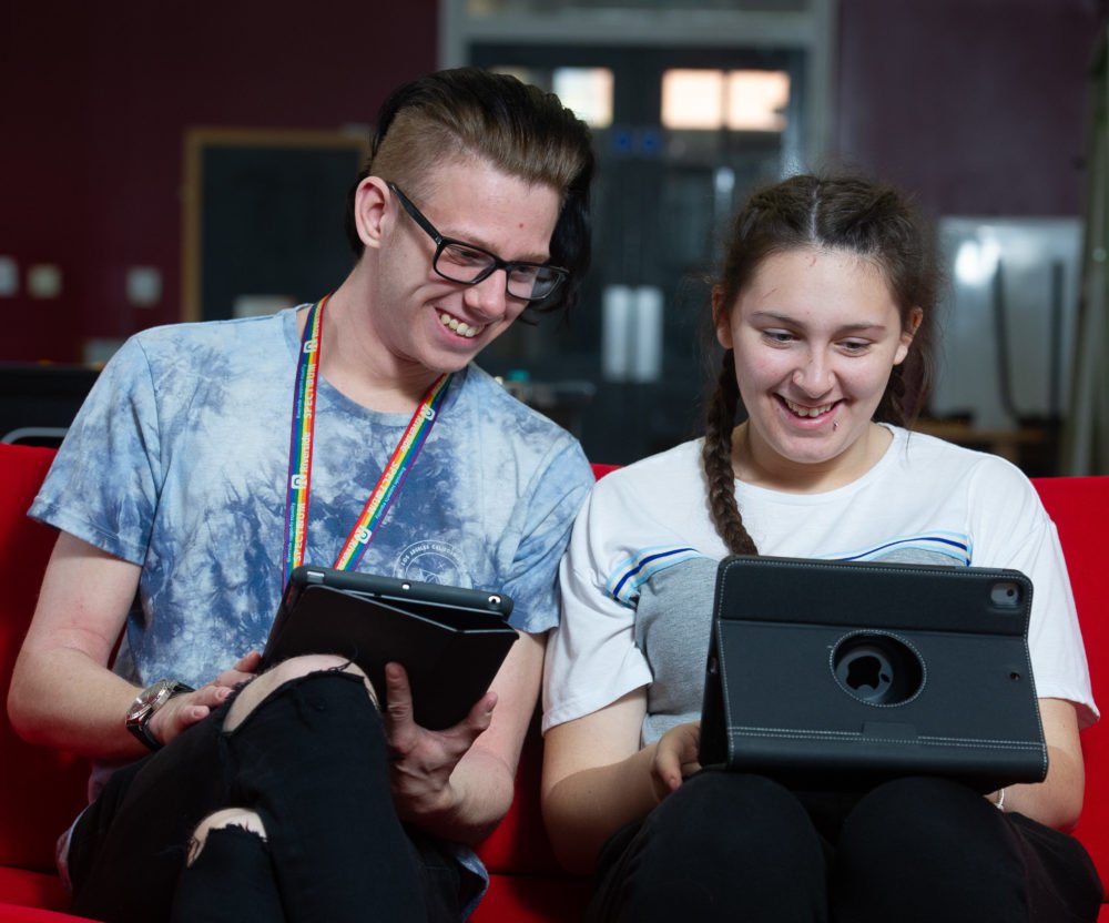 Two young adults using tablets