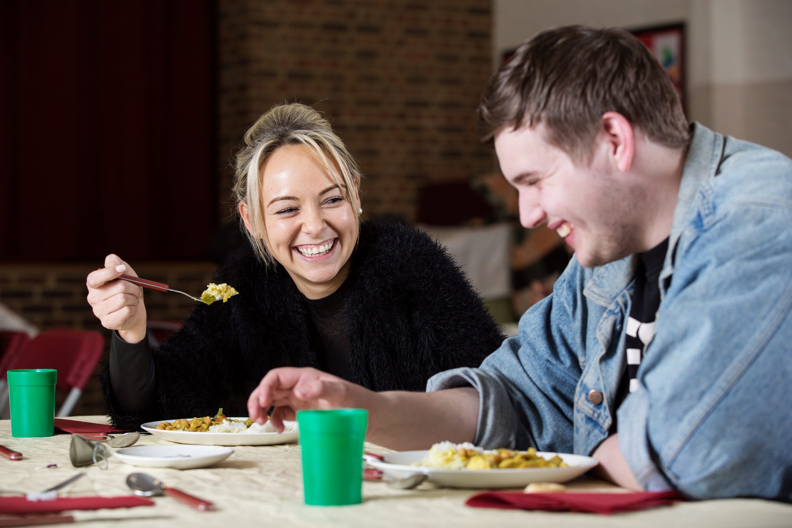Two people eating together at a church winter night shelter