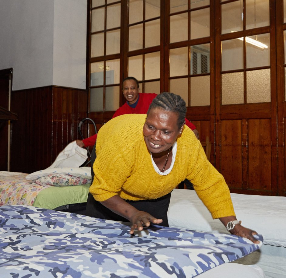 Two people making beds at a church winter night shelter