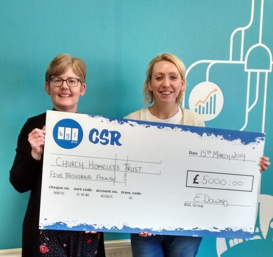 Wakefield hostel cheque presentation - BGL Group. Suzanne Bailey and Jamie Lyons holding big cheque and smiling