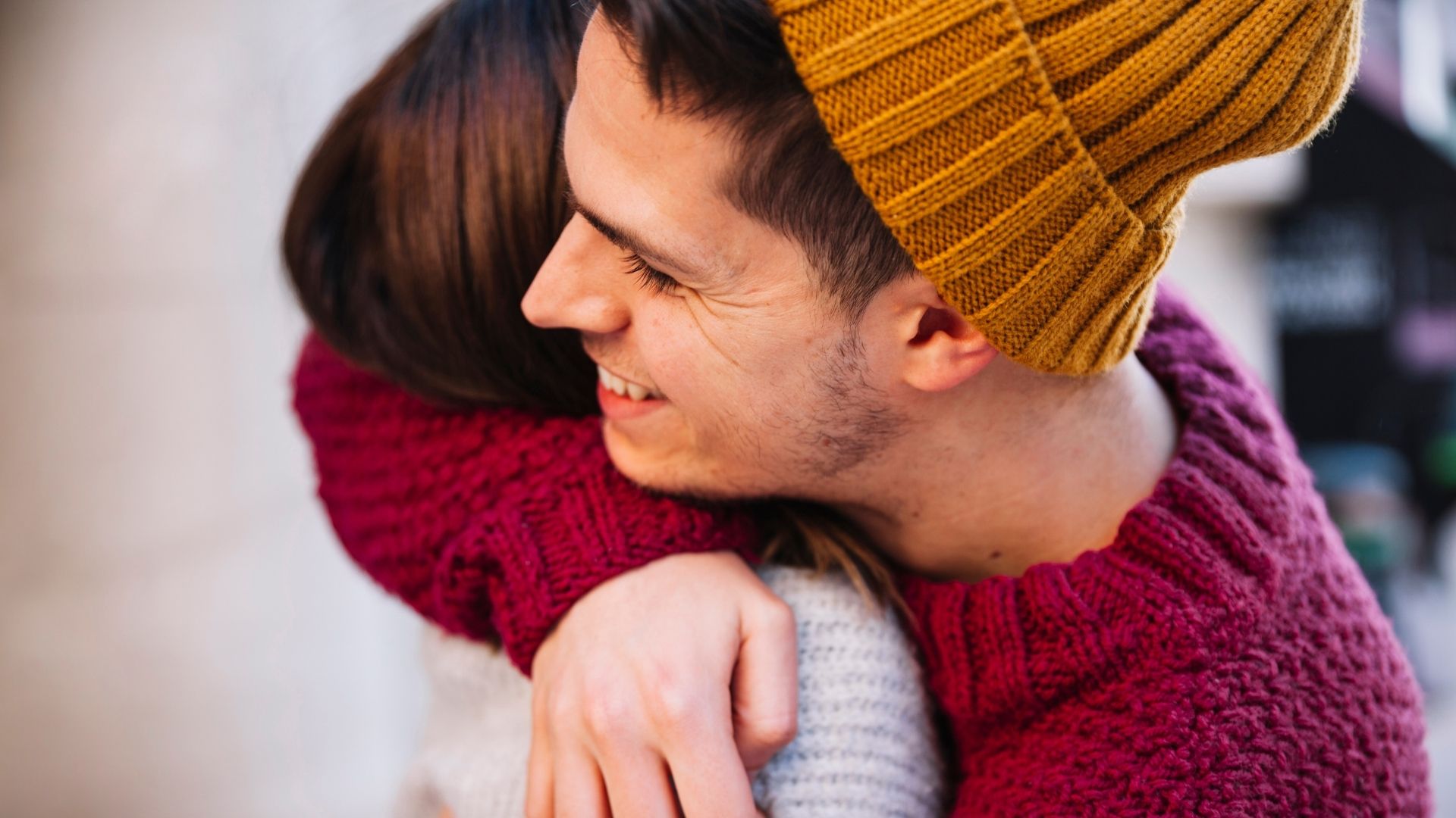world homeless week website banner shows a young man with dark hair and stubble wearing a yellow beanie hat hugging a woman with brown hair