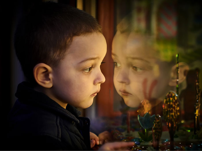 A toddler stares out of a window at Christmas time