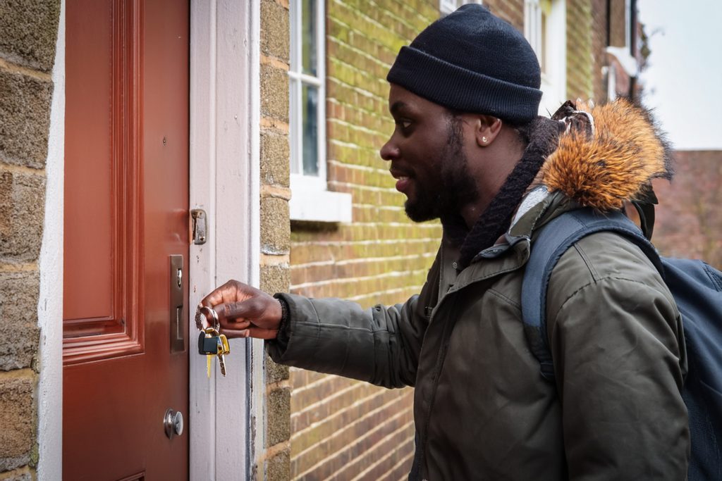 Man with house keys in hand about to open door of small dwelling in a city in England 
