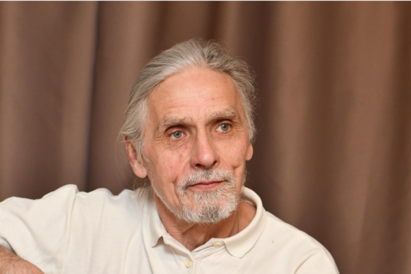 Photographer of a over 55 year old man with grey hair and a beard and a white polo top on