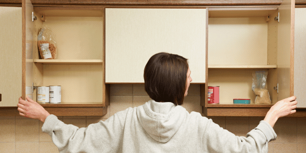 Woman looking into empty kitchen cupboards - The scale of temporary accommodation